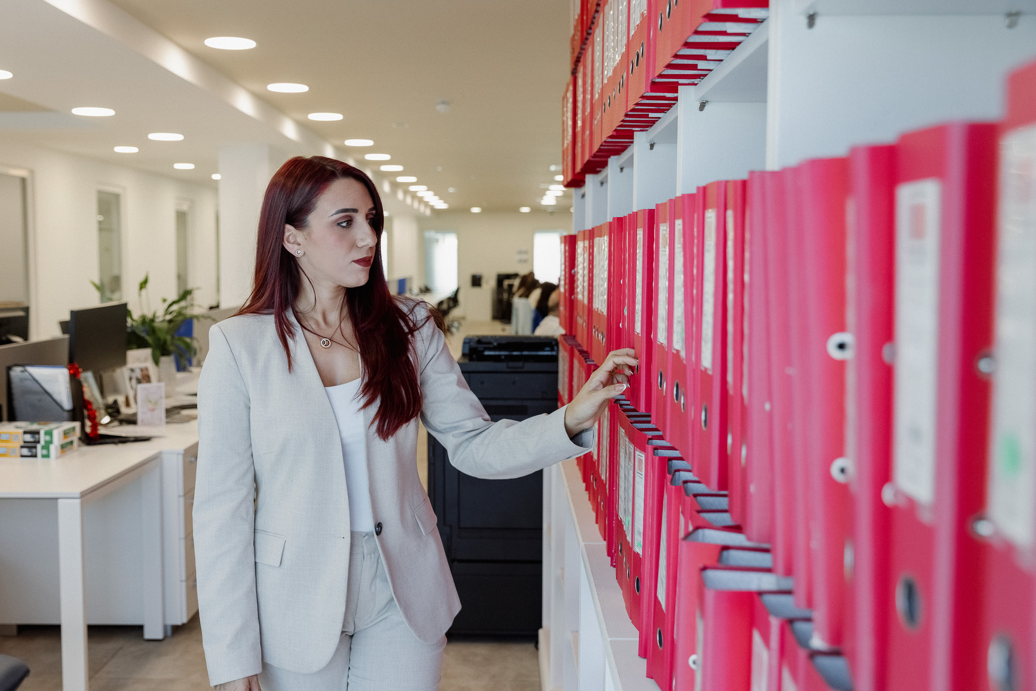 Female staff member at a filing shelf with red folders